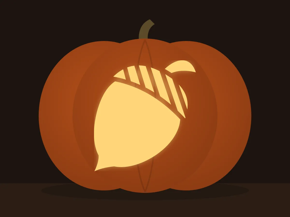 Carved pumpkin with the acorn pattern, lit by a candle