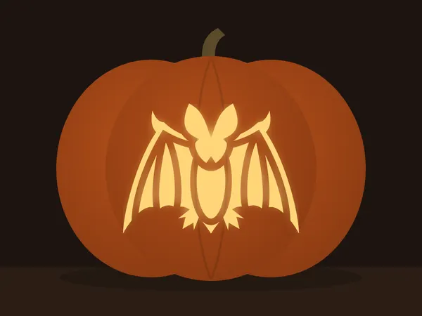 Carved pumpkin with the bat pattern, lit by a candle