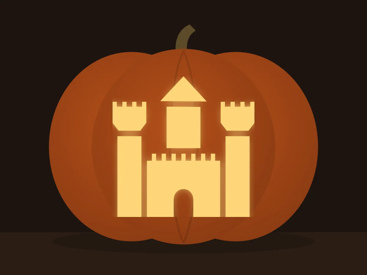 Carved pumpkin with the castle pattern, lit by a candle