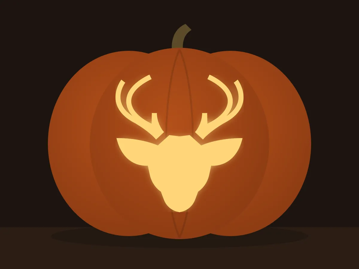 Carved pumpkin with the deer head pattern, lit by a candle