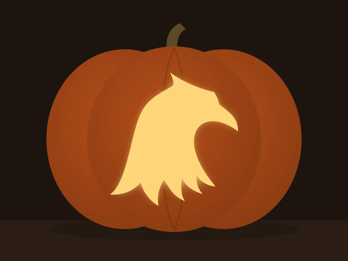 Carved pumpkin with the eagle head pattern, lit by a candle