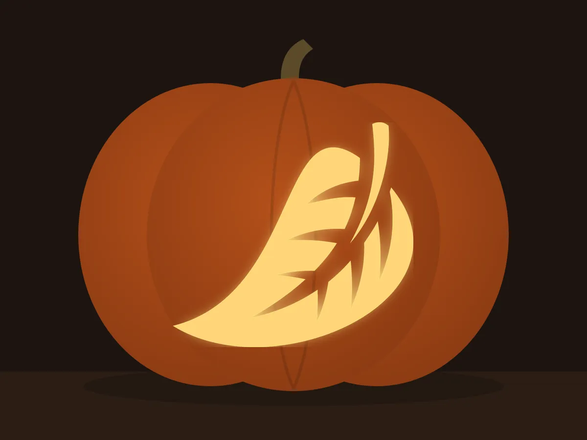 Carved pumpkin with the falling leaf pattern, lit by a candle