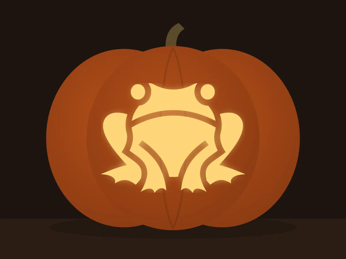 Carved pumpkin with the frog pattern, lit by a candle