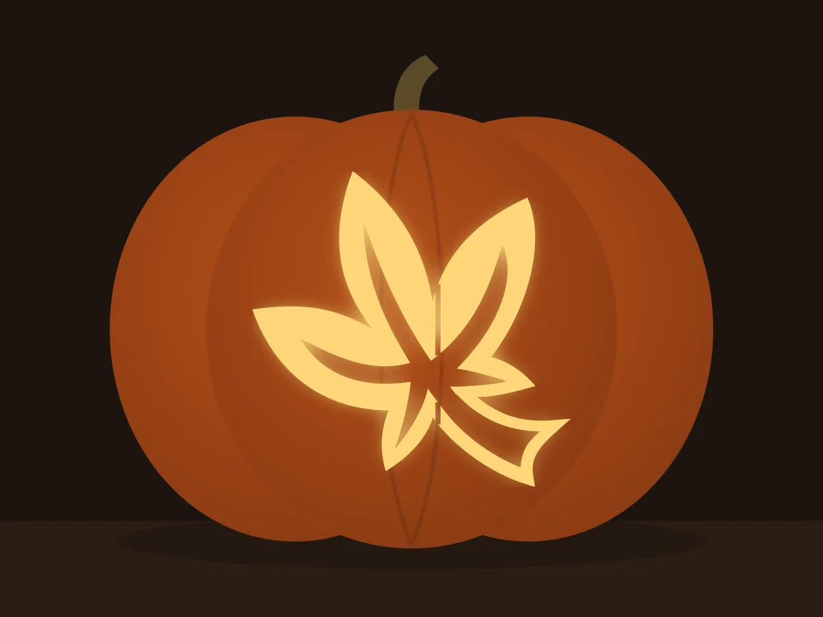 Carved pumpkin with the maple leaf pattern, lit by a candle