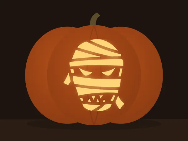 Carved pumpkin with the mummy face pattern, lit by a candle