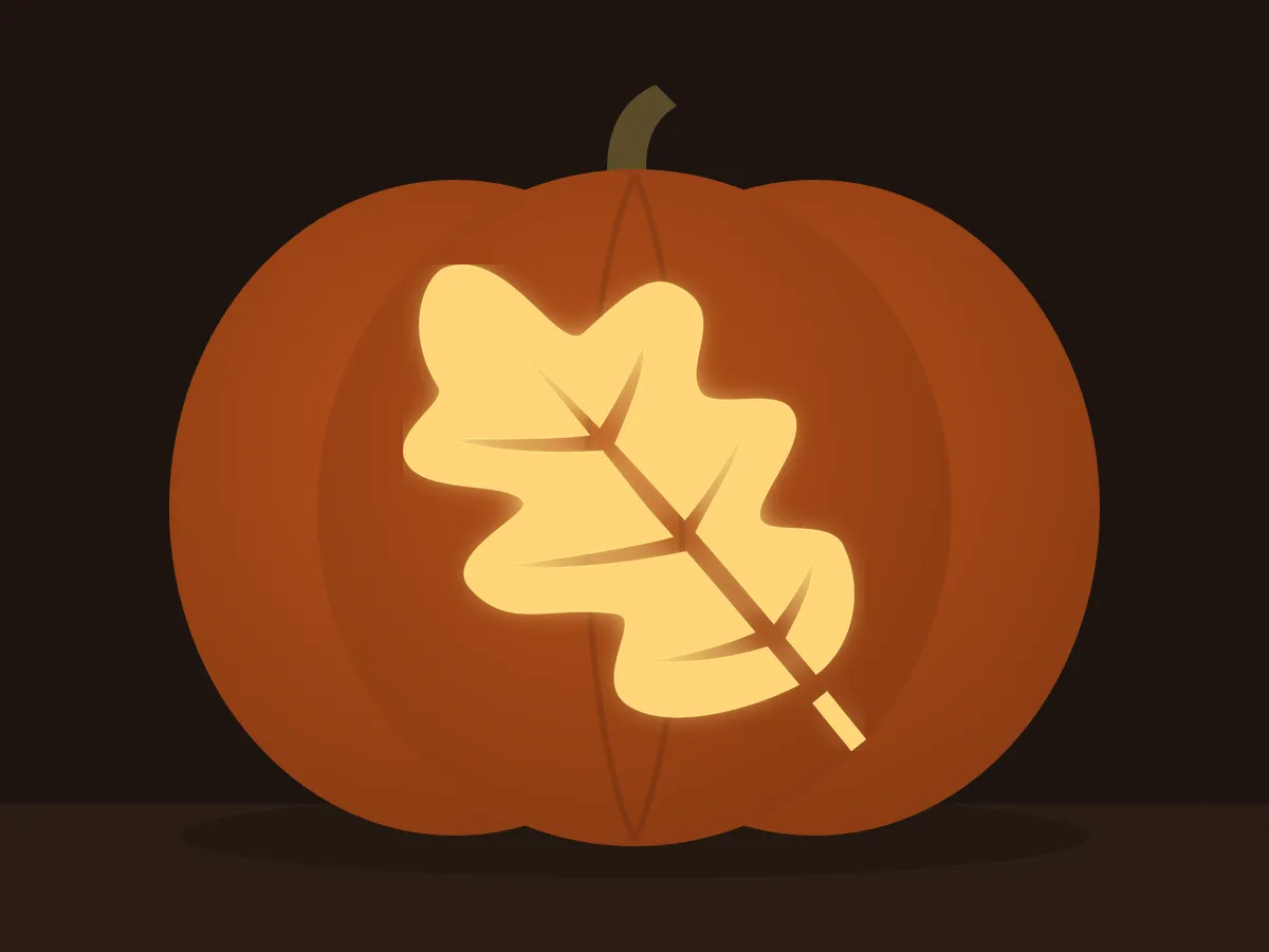 Carved pumpkin with the oak leaf pattern, lit by a candle