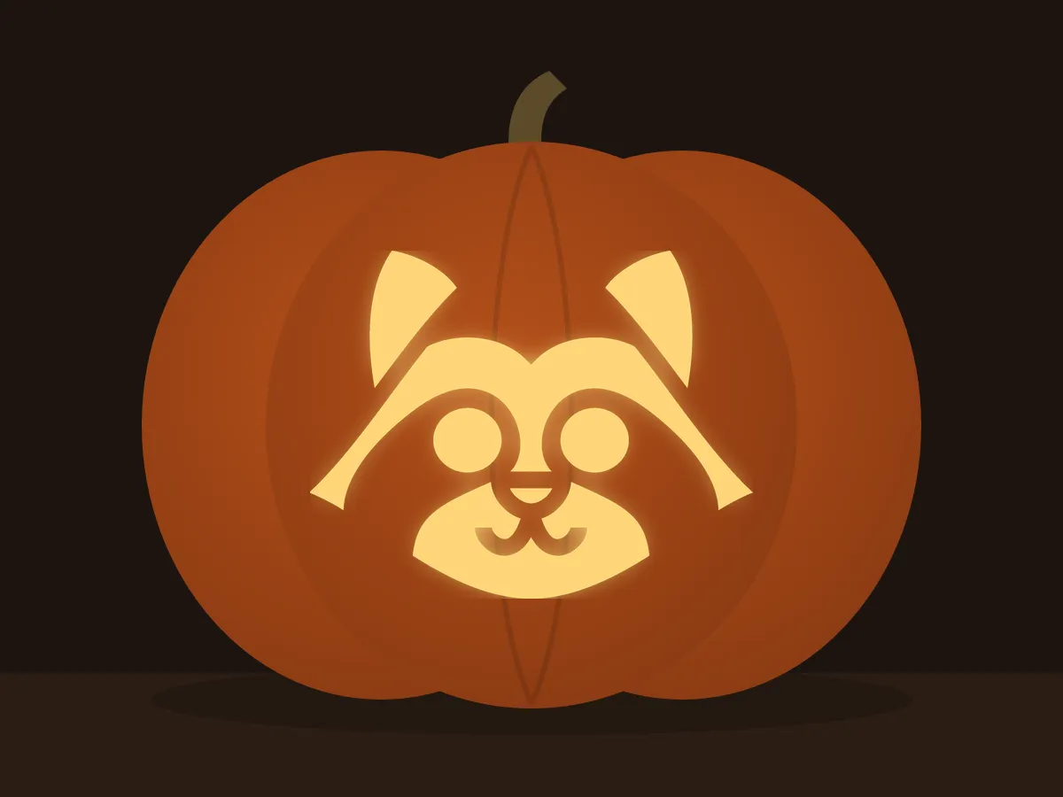 Carved pumpkin with the raccoon pattern, lit by a candle