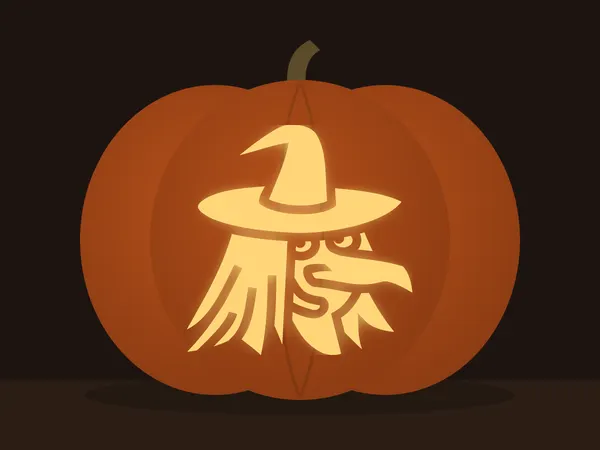 Carved pumpkin with the witch face pattern, lit by a candle